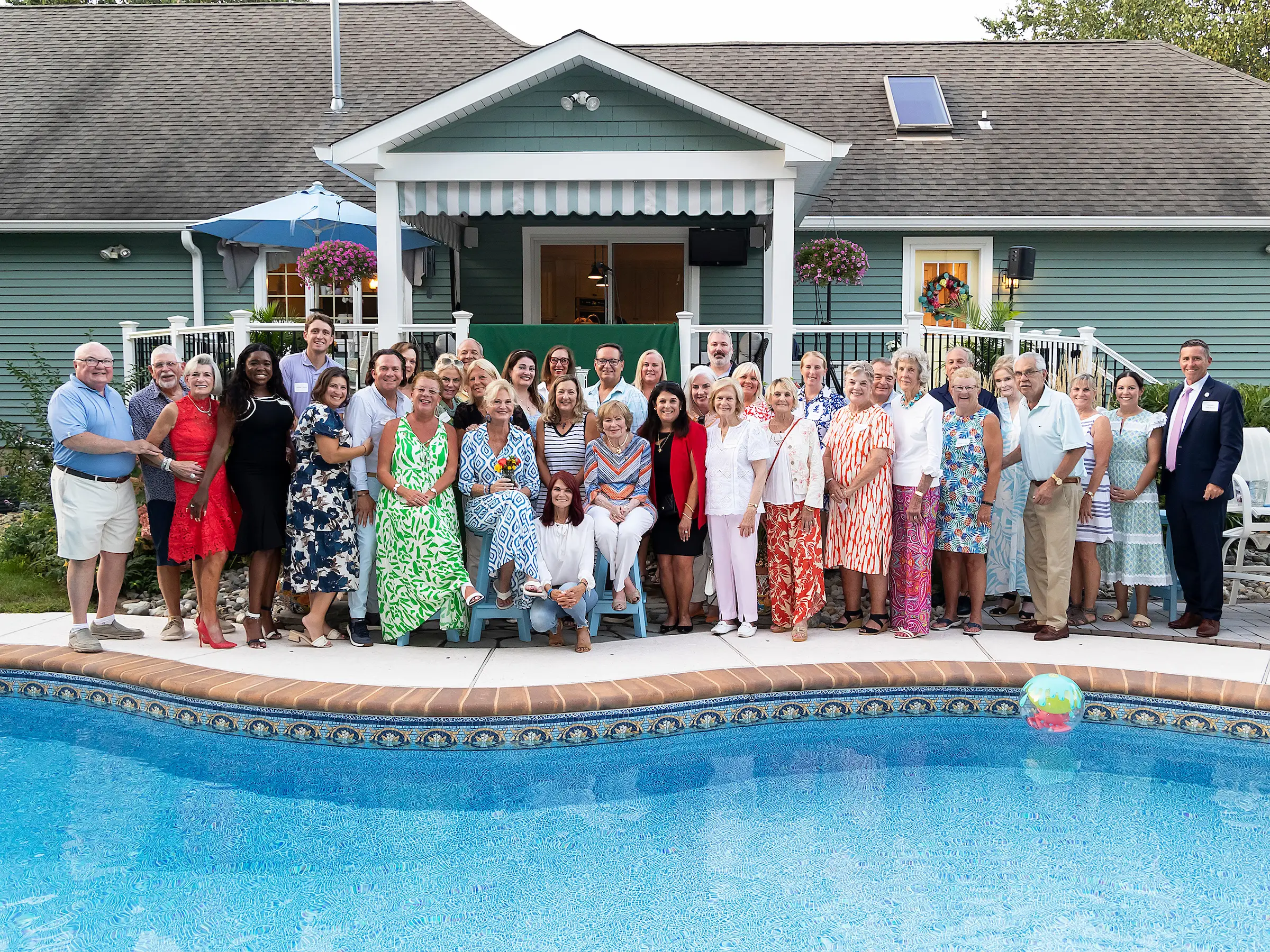 Group of people posing by a pool at a backyard party