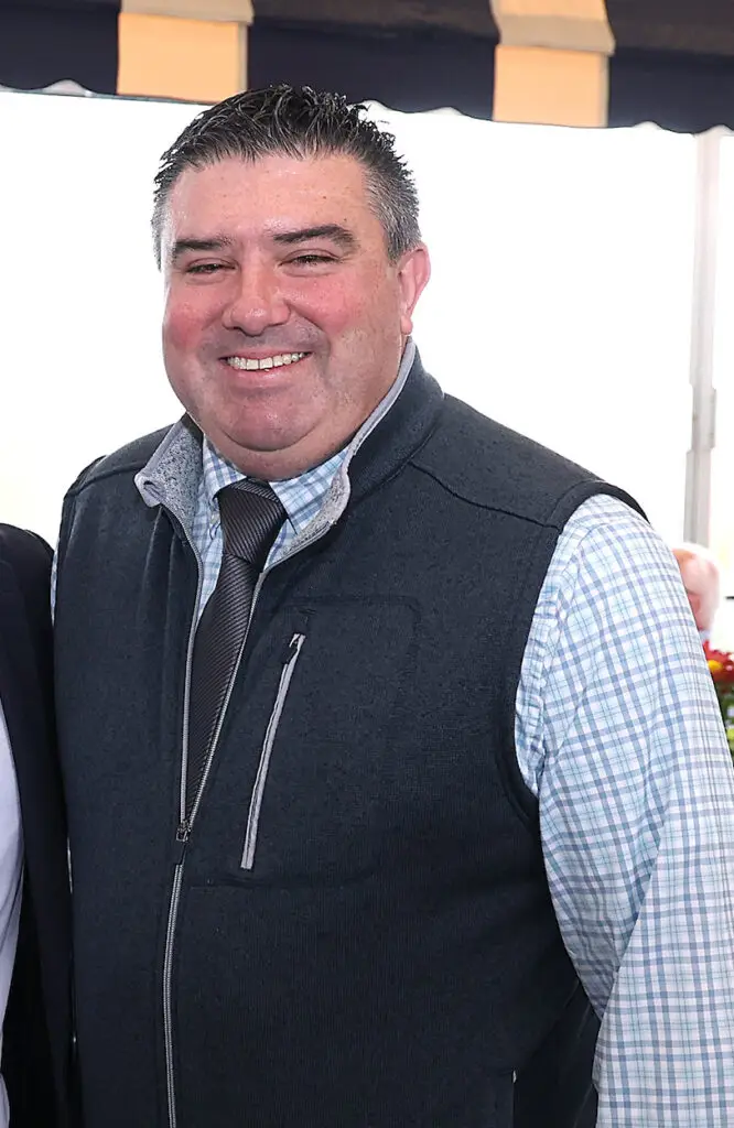 Man in vest and tie smiles at an event.