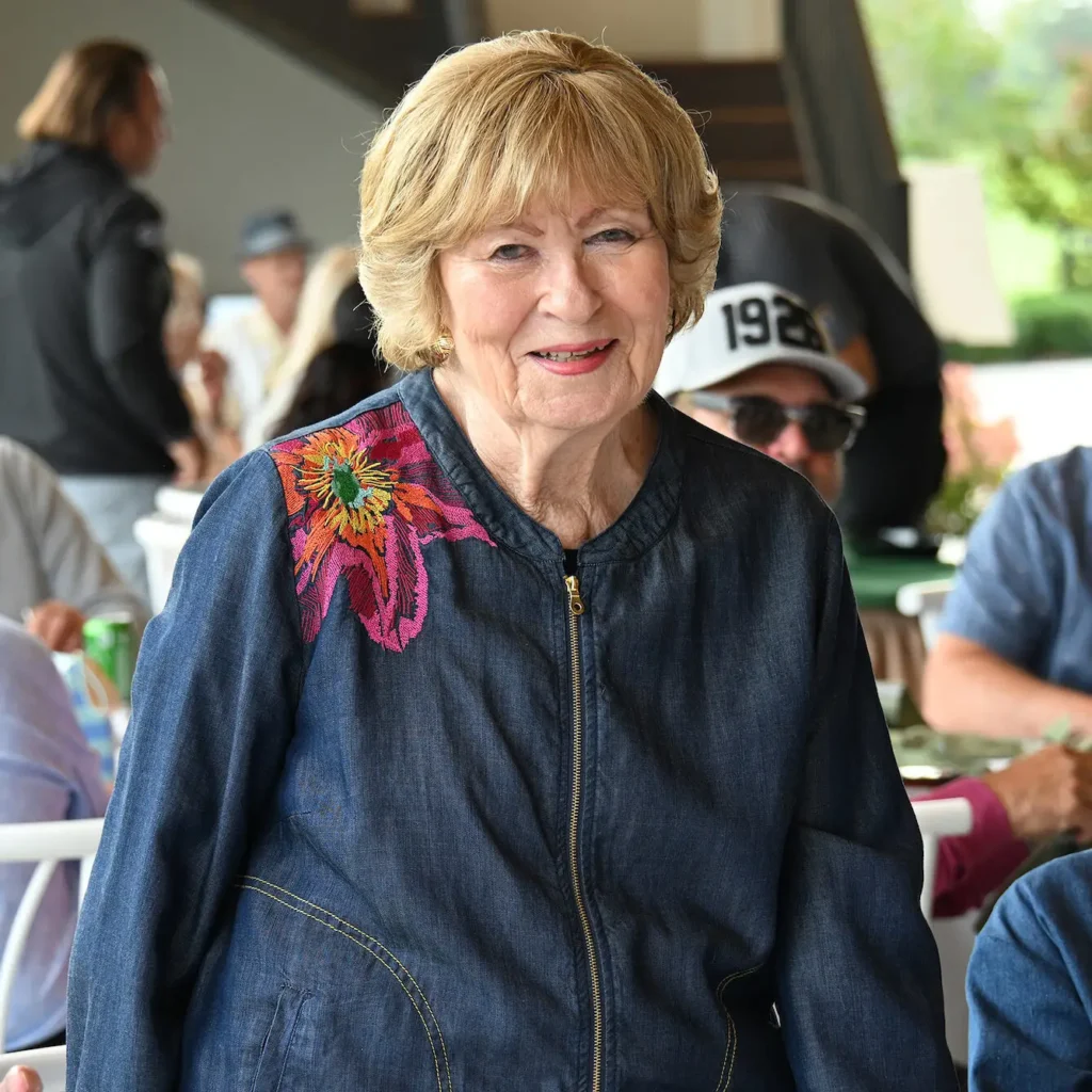 Portrait of a smiling woman in a denim jacket with a floral design.