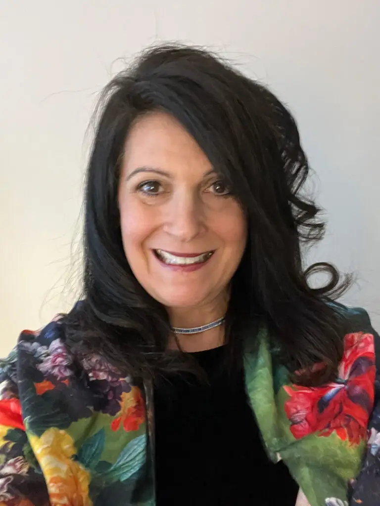 Portrait of a woman with dark hair and a colorful floral jacket.