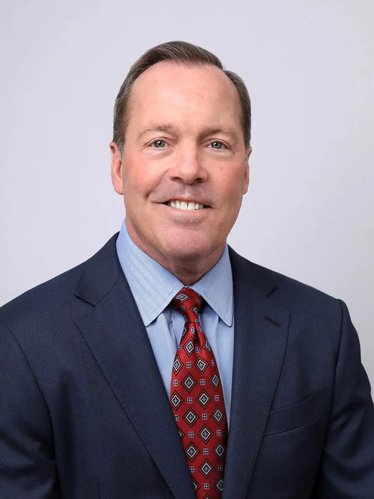 A man wearing a blue suit and a maroon tie smiling