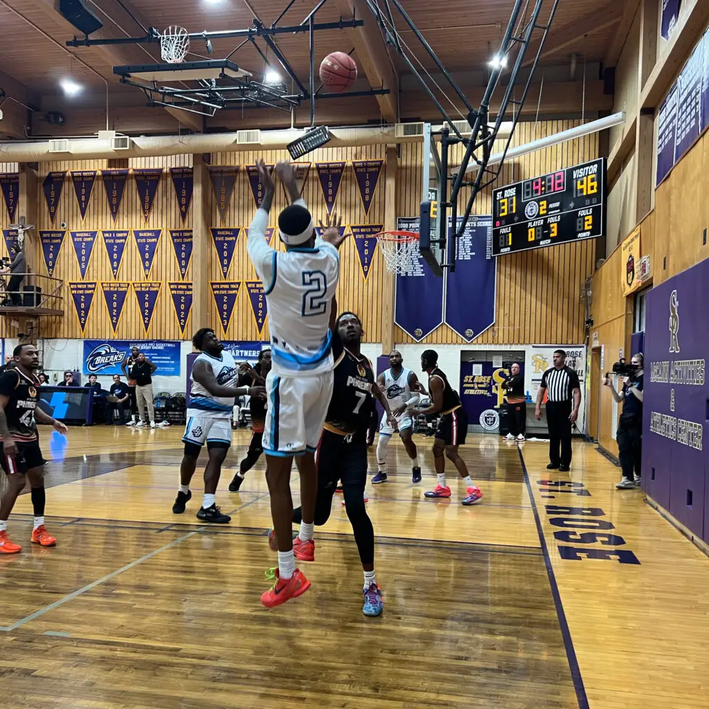 Basketball player in white/blue #2 jersey shooting during game. Scoreboard visible.